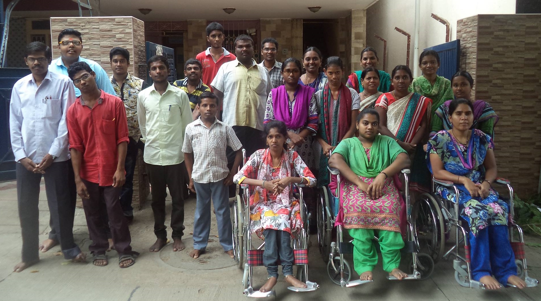 A Group photo of Agape with many persons with disabilities standing at the entrance of the building